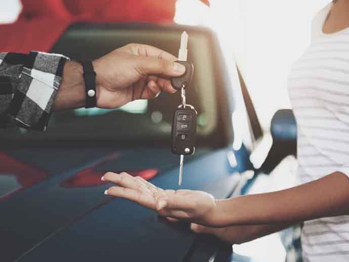 Car salesman handing over new car keys to his customer
