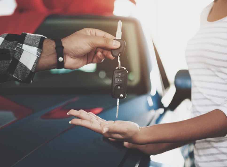 Car salesman handing over new car keys to his customer