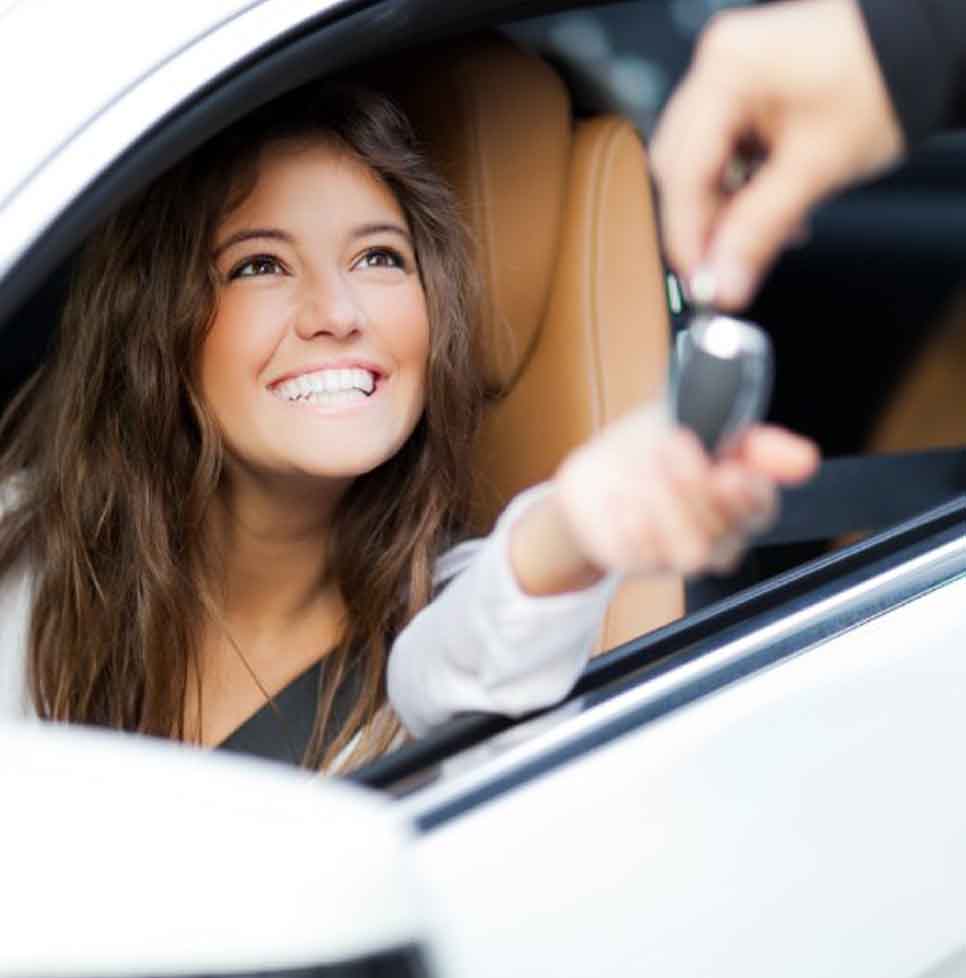 Smiling customer recieving keys inside their new car