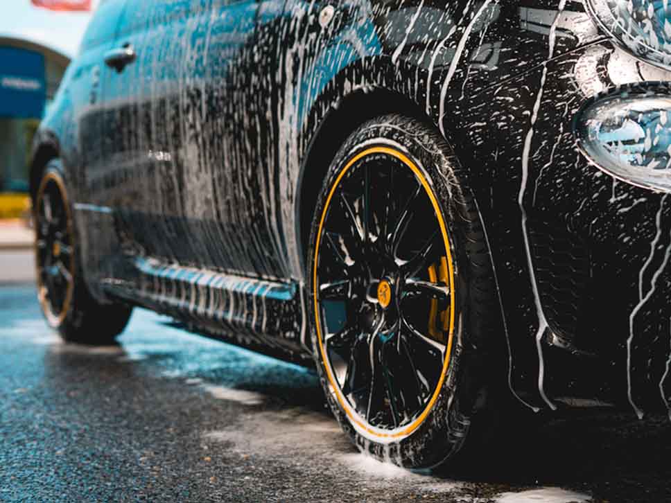 An Abarth car with soap dripping down it after carwash