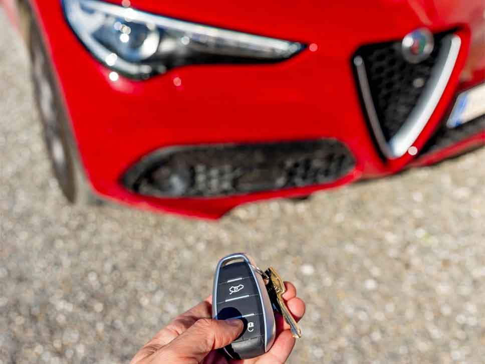 Hand using remote car key to open Alfa Romeo Stelvio