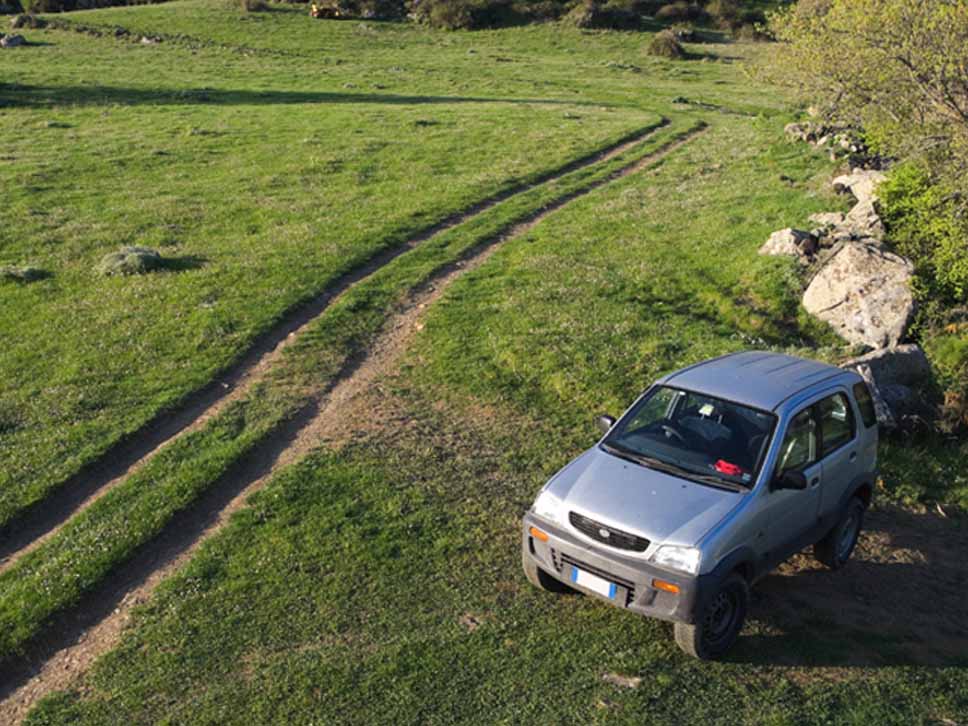 Daihatsu off roader parked up on the side of a dirt track