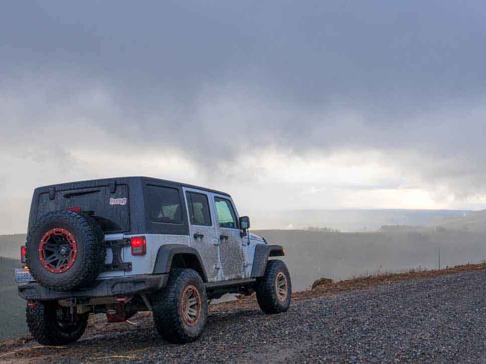 Jeep pulled over on the side of a gravel track looking at scenery