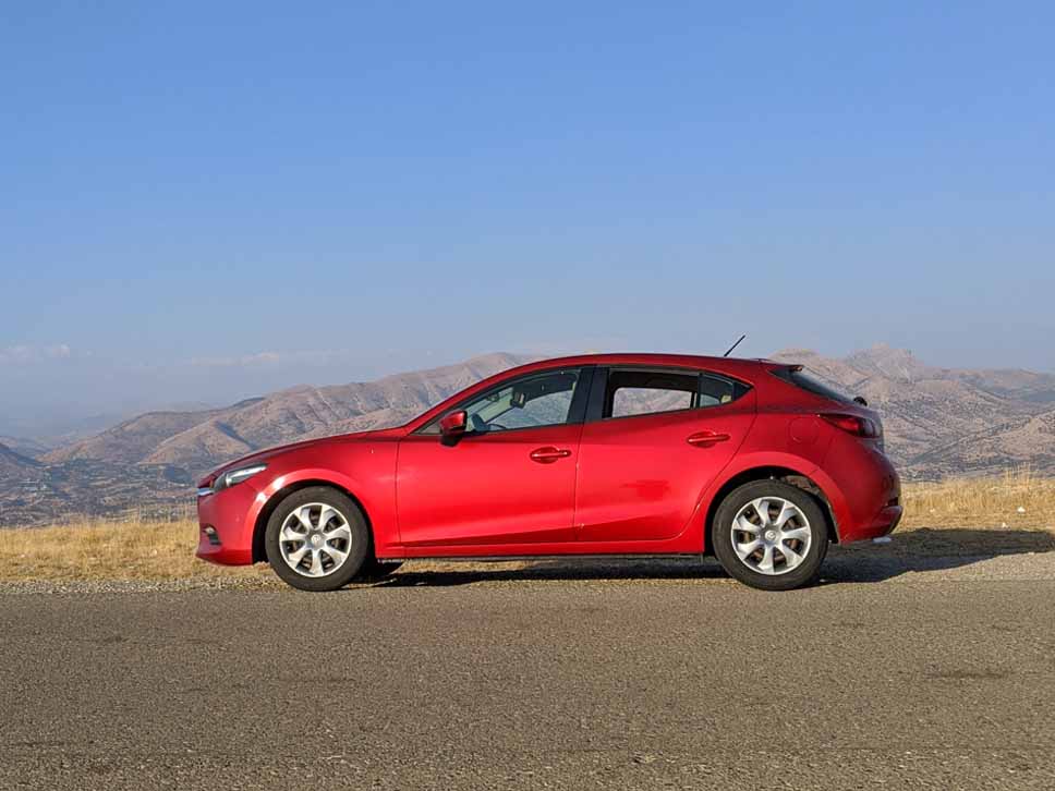 Side profile of a red Mazda on scenery
