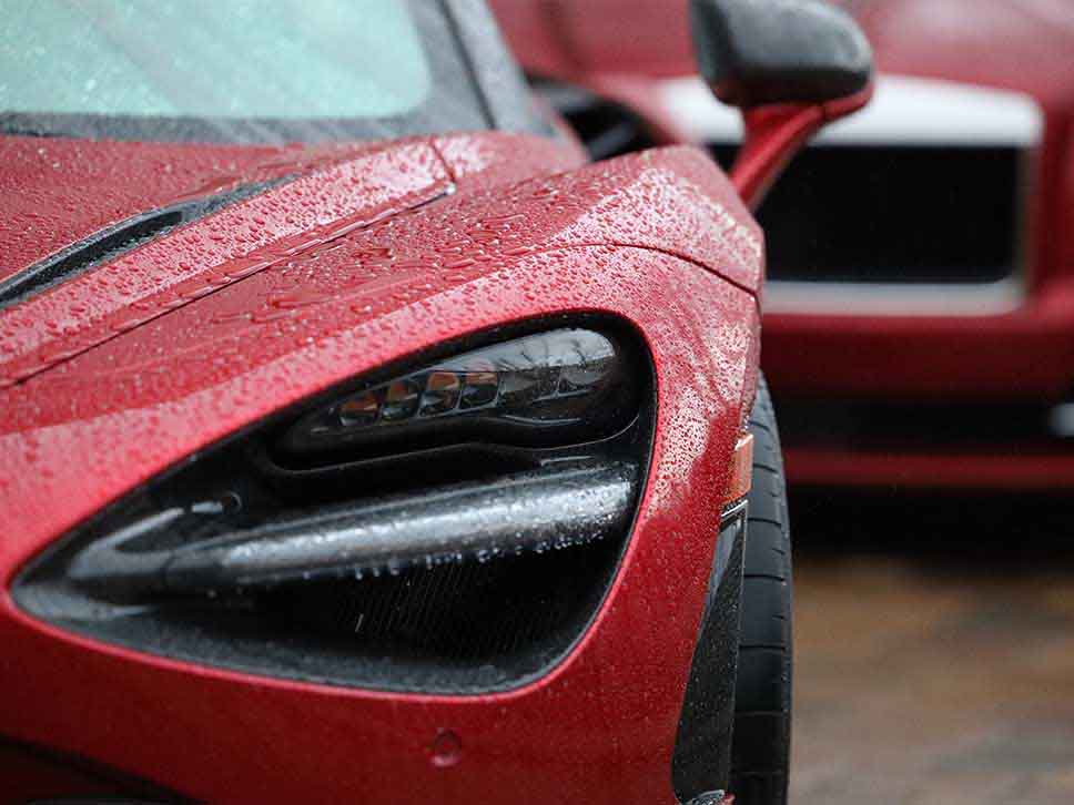 Red McLaren in the rain headlight close up
