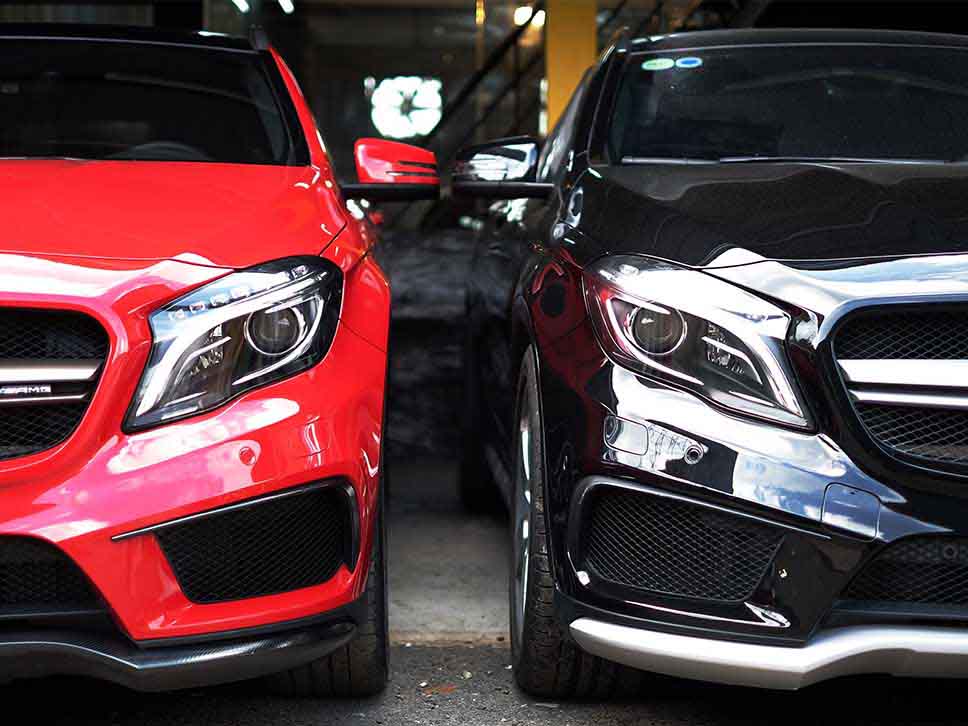 A red Mercedes and a black Mercedes side by side