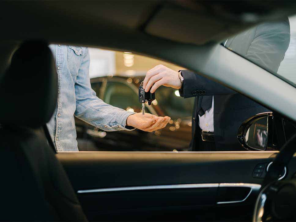 Car salesman handing over new car keys to his customer